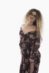 Woman with curly hair and floral dress posing on white background