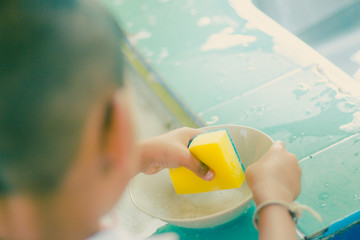 Close up to hands of .Kindergarten student is cleaning dish.