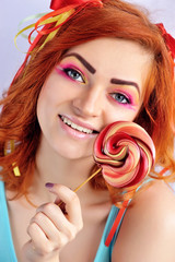 Young attractive red-haired girl with colorful lollipop
