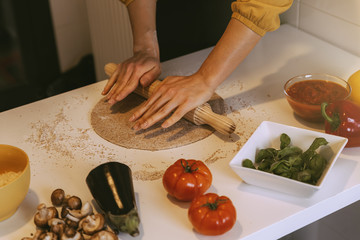 Woman preparing delicious pizza with healthy ingredients.