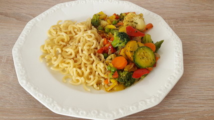 pasta cooked with vegetables in a white plate