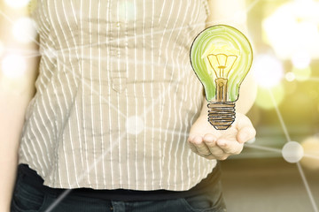 Woman holding a green light bulb with as "green thinking" concept  on a sunny day