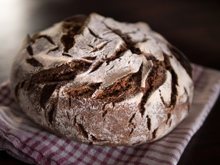 freshly baked round coutry bread on a towel and wooden table