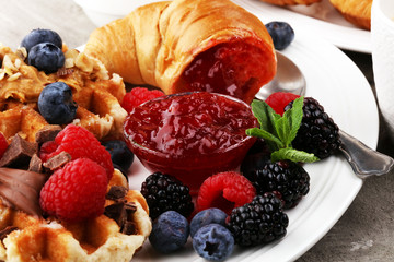 Delicious breakfast with fresh croissants and ripe berries and jam