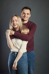Portrait of a beautiful young couple in love posing at studio over dark background