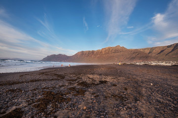 Unidentifiable surfers in famous Famara beach in Lanzarote, Canary islands, Spain.