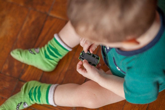 Little Cute Boy Playing With A Plastic Toy Truck