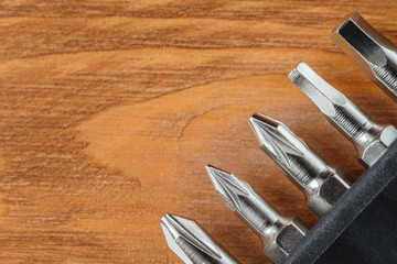 A set of tools collection from heads for screwdriver (bits) on a wooden table with copy space. Flat lay. Corner arrangement.