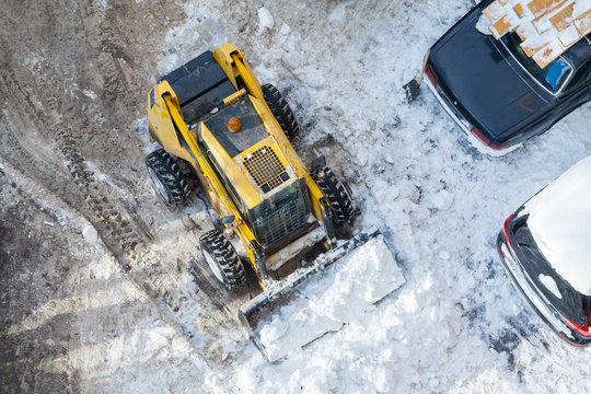 Top view on a snow-removing machine cleaning the parking