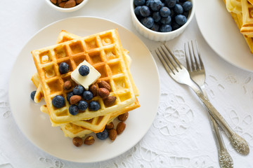 Healthy breakfast. Belgian waffles with butter, blueberry and nuts on white tablecloth. Selective focus