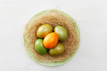 Happy Easter concept. Easter eggs in nest on white wooden table. Top view.