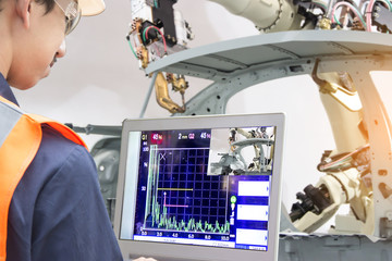 Industry 4.0 Robot concept .Engineers use laptop computers for machine maintenance, automation...