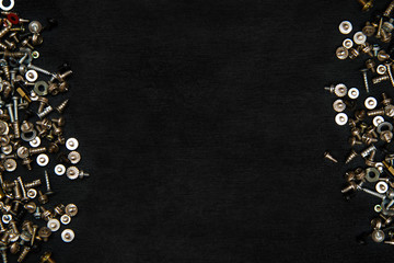 Silvery bolts and screws on a black board