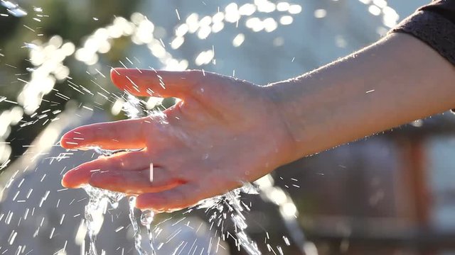 Woman hand playing with artesian fountain water