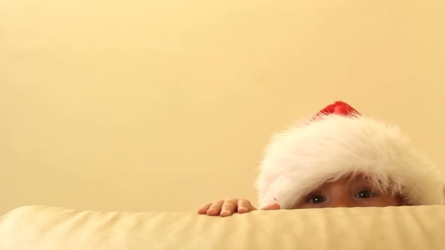 Eyes only of baby with Santa Claus cap lurching behind coach