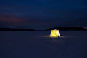 Night fishing. Yellow Fishing Shelter Of Tent On Ice At Night Winter.
