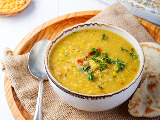 Lentil soup with pita bread in a ceramic white bowl on a wooden background. Close up.