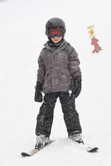 Fototapeta na wymiar Child boy skiing in mountains. Active teenager kid with safety helmet and goggles. Ski race for young children. Winter sport for family. Kids ski lesson in alpine school. Young skier racing in snow 