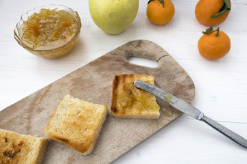 A sandwich with fruit jam and a knife that spread the jam on fried bread.