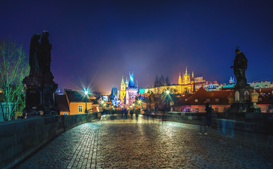Cityscape of Prague with Charles bridge, medieval towers and colorful buildings at night, Czech Republic