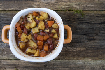 Appetizing beautiful soup with potatoes, onions, carrots and beans. On an old wooden background and close-up. Top view and copy space.