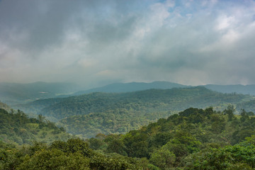 Talakaveri, India - October 31, 2013: Blue and gray clouds over the green jungle covered highlands around the spring of the Kaveri River sanctuary.