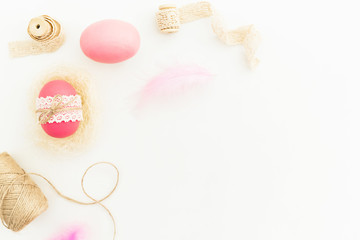 Obraz premium Frame of Easter pink eggs with twine, feathers and tapes on white background, Top view, Fat lay. Easter holiday