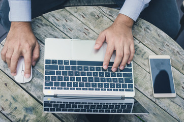 attractive hand of business man using laptop working typing on key board with coffee cup in coffee shop.