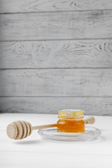 Glass jar of honey on a textile tablecloth. Glass saucer and wooden spoon, kitchen utilities. Home made organic mask ingredients. Healthy eco lifestyle. Food blog illustrations. Honey and lemon