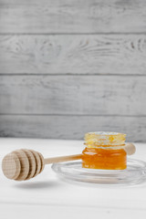 Glass jar of honey on a textile tablecloth. Glass saucer and wooden spoon, kitchen utilities. Home made organic mask ingredients. Healthy eco lifestyle. Food blog illustrations. Honey and lemon