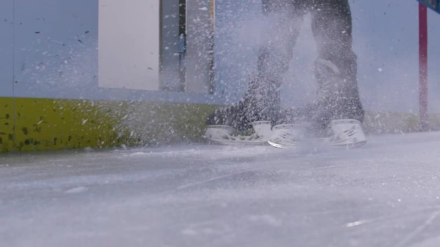 Young hockey player skates to a stop spraying snow across the ice and then gets off the ice in slow motion action shot