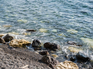 sea blue waves and surf breaking on coastal rocks. sea water and rocks in a Sunny day