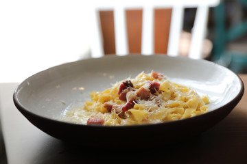 spaghetti carbonara white sauce with bacon on wood background in restaurant