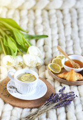 Naklejka na ściany i meble Cup with lavender tea, citrus and honey, croissant, white pastel giant knit blanket, bedroom, flowers tulips, spring, woman day, morning concept