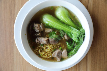 Chinese noodles with pork on wood background