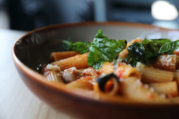 Pasta with sausage in tomato sauce on wood background , italian food