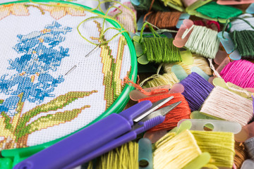 The process of cross-stitch. Canvas on hoops, needles, embroidery floss and pattern.