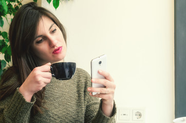 Beautifur girl using smartphone and drinking coffee