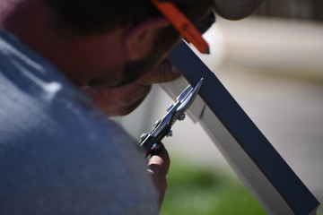 Man cutting metal with tin snips.