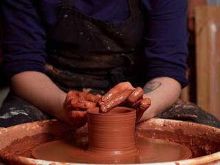 production process of pottery. Forming a clay mug on a potter's wheel.