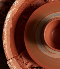 production process of pottery. mug of red clay on a potter's wheel.