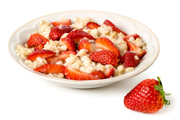 Bowl of oatmeal with strawberries and strawberry on white background.