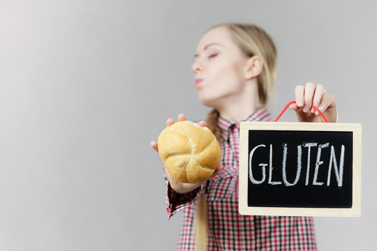 Woman holding board with gluten sign and bun bread