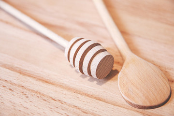 wooden wand for honey and wooden spoon on wooden board