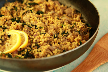 Vegetarian couscous with mushrooms and spinach. Vegan dish with millet in the frying pan. Close up.