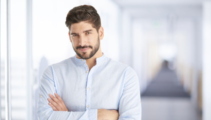 Confident young businessman portrait. Portrait of a casual young man standing at office, looking at camera and smiling. 