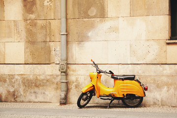 Yellow vintage moped on a brown wall background. On the street of Berlin