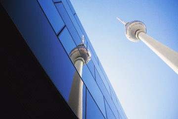 The Berlin TV tower and its reflection in a glass building on a sunny day