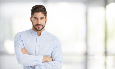 Confident young businessman portrait. Portrait of a casual young man standing at office, looking at camera and smiling. 