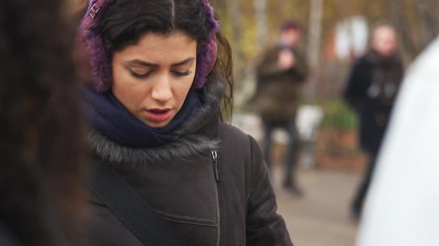 Young Woman Wearing Ear Muffs Checking Mobile Phone